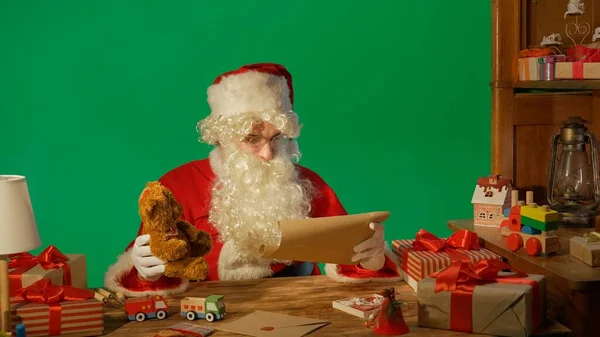 Noel Baba Hediyelerle Masada Yeşil Bir Arkaplanda Bir Mektup Paketi — Stok fotoğraf