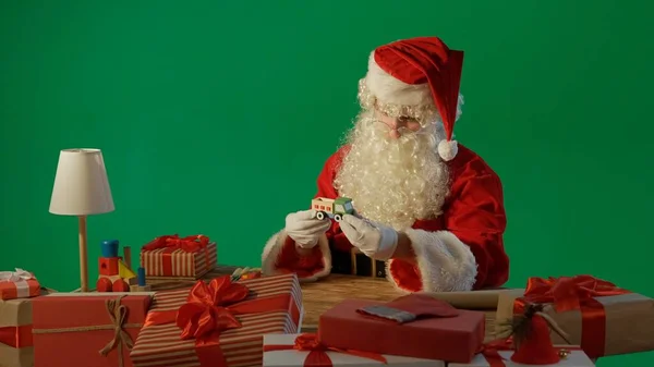 Masadaki Noel Baba Yeşil Arka Planda Tahta Bir Oyuncağı Elinde — Stok fotoğraf