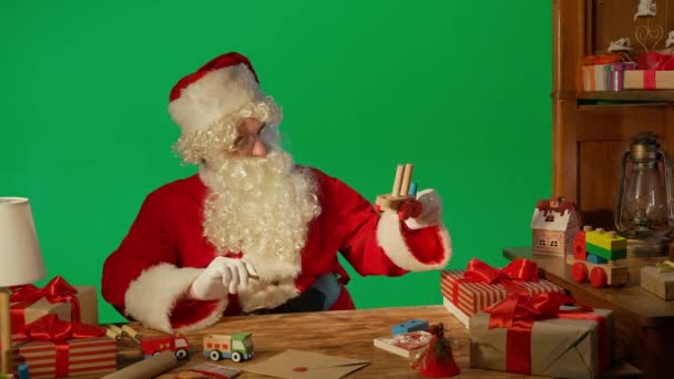 Санта Клаус Столом Подарунками Фарбами Дерев Яна Іграшка Зеленому Фоні — стокове відео
