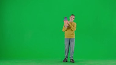 Modern çocuk okulu ve eğlence zamanı reklam konsepti. Krom anahtar yeşil ekrandaki çocuk portresi. Sıradan giyinen, kaykay tutan, havalı bir yüz ifadesi olan, kameraya gülümseyen bir çocuk..