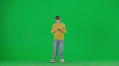 Modern çocuk okulu ve eğlence zamanı reklam konsepti. Krom anahtar yeşil ekrandaki çocuk portresi. Gündelik kıyafet giymiş okul çocuğu joystick ile video oyunu oynuyor, üzgün yüzünü ve hareketini kaybediyor..