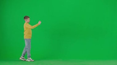 Modern çocuk okulu ve eğlence zamanı reklam konsepti. Krom anahtar yeşil ekrandaki çocuk portresi. Gündelik kıyafetlerle gezen ve akıllı telefondan ailesiyle konuşan okul çocuğu..