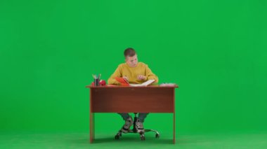 Modern çocuk okulu ve eğlence zamanı reklam konsepti. Krom anahtar yeşil ekrandaki çocuk portresi. Okul çocuğu masada oturuyor, okul ödevi yapıyor, deftere yazıyor, uzaklaşıyor..