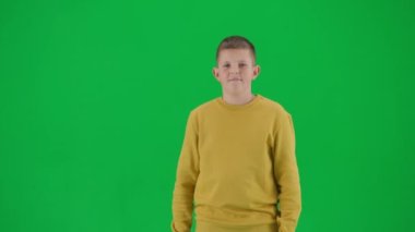 Modern çocuk okulu ve eğlence zamanı reklam konsepti. Krom anahtar yeşil ekrandaki çocuk portresi. Sıradan bir kaykaylı öğrenci, havalı bir ifade, kameraya gülümsüyor. Orta çekim.