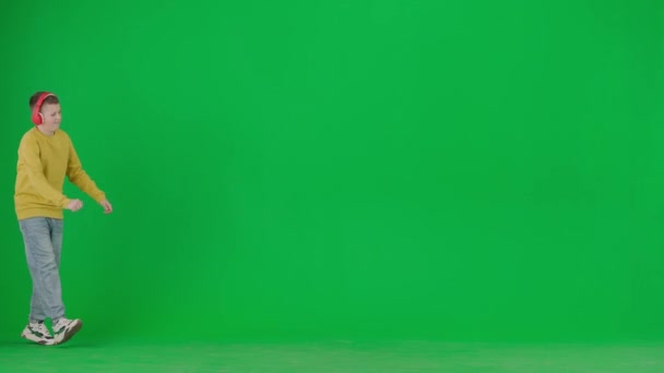 现代儿童学校和闲暇时间广告的概念 彩色键绿色屏幕上的男孩肖像 穿着休闲装 头戴耳机 走路和跳舞 听音乐的学童 — 图库视频影像
