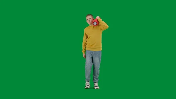 学生和闲暇时间的创意概念 彩色键绿色屏幕上的小男孩的肖像 穿着牛仔裤的男孩拿着音乐喇叭走路 听音乐 全身上下正中枪 — 图库照片