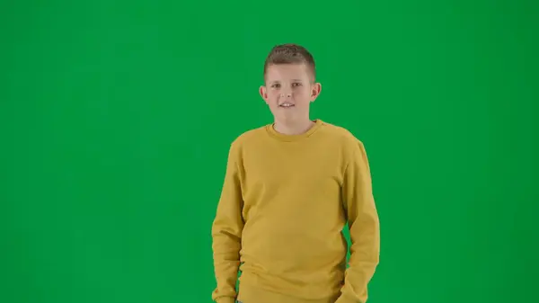 学生和闲暇时间的创意概念 彩色键绿色屏幕上的小男孩的肖像 男孩穿着牛仔裤站在那里看着摄像机正面的表情 中间身体前射 — 图库照片