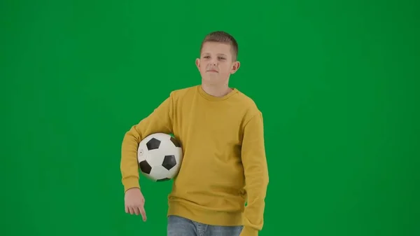 学生和闲暇时间的创意概念 彩色键绿色屏幕上的小男孩的肖像 穿着牛仔裤的男孩拿着足球走来走去 环顾四周 中间身体前射 — 图库照片