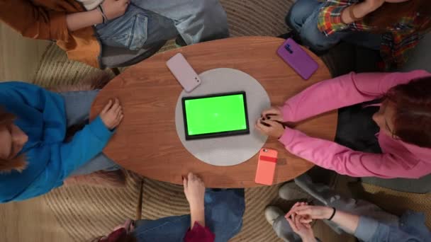 コーヒーテーブルに座っている女性学生のトップビューは 中央に緑色のスクリーンが付いているタブレットで 閉じます 広告スペース — ストック動画