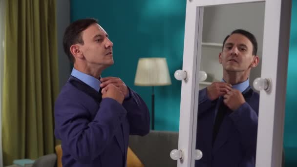 厳格なスーツを着た男が 鏡の前でリビングに立っている 男は自分自身に話しかけ 自分を応援している スプリットパーソナリティ — ストック動画