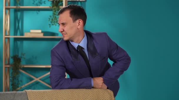 Takım Elbiseli Bir Adam Oturma Odasındaki Kanepenin Arkasına Yaslanarak Duruyor — Stok video