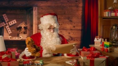 Noel Baba hediyelerle masada ve evinde bir mektup okuyor.