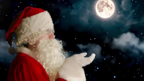 サンタクロースは彼の手を吹き飛ばし 夜空の背景に対して多くの白い雪を吹く — ストック動画
