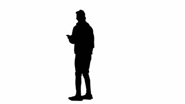 Seyahat eden yaratıcı havaalanı reklam konsepti. Gezgin portresi beyaz arka plan alfa kanalında izole edildi. Akıllı telefonlu ve uçuş panosunu kontrol eden bir adamın silueti..