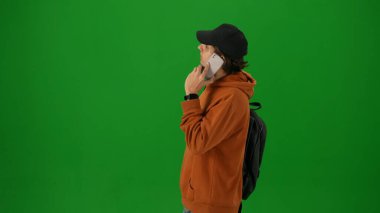 Havaalanı yaratıcı reklam konsepti. Krom anahtar yeşil ekran arka planında izole edilmiş insan portresi. Yakın çekim genç adam akıllı telefondan konuşuyor kalkış panosuna bakıyor..