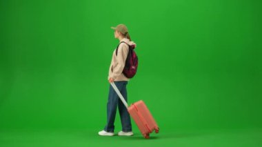 Uçak kreatif havaalanı reklam konseptiyle seyahat etmek. Krom anahtar yeşil ekran arka planında izole edilmiş gezgin portresi. Bavullu genç kız kalkış tahtasına bakıyor..