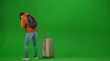 Uçak kreatif havaalanı reklam konseptiyle seyahat etmek. Krom anahtar yeşil ekran arka planında izole edilmiş gezgin portresi. Genç adam uçağına geç saatte kalkıyor. Yüzü asık..