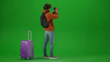 Uçak kreatif havaalanı reklam konseptiyle seyahat etmek. Krom anahtar yeşil ekran arka planında izole edilmiş gezgin portresi. Bavullu genç adam kamerasıyla fotoğraf çekiyor..