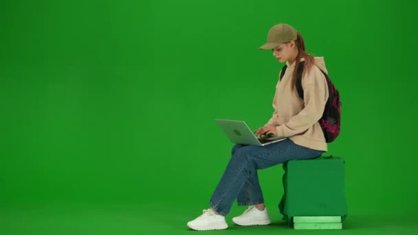 飛行機によるクリエイティブな空港広告コンセプト クロマキーの緑色の背景に隔離された旅行者の肖像画 オンラインラップトップにテキストを座って飛行を待っている若い女の子 — ストック動画