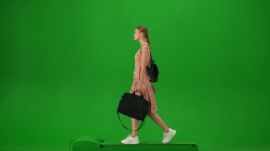 Uçak kreatif havaalanı reklam konseptiyle seyahat etmek. Krom anahtar yeşil ekran arka planında izole edilmiş gezgin portresi. Laptop çantasıyla yürüyen ve etrafa bakan genç bir kız..