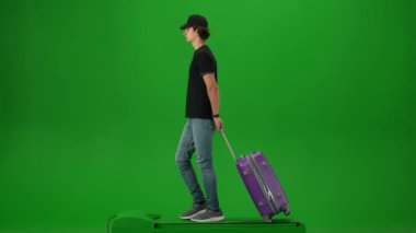 Uçak kreatif havaalanı reklam konseptiyle seyahat etmek. Krom anahtar yeşil ekran arka planında izole edilmiş gezgin portresi. Şapkalı genç adam yürüyor ve etrafa bakıyor..