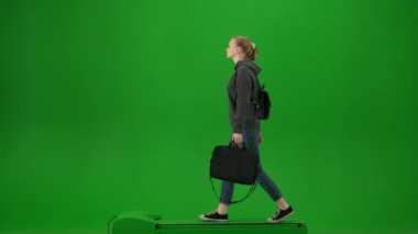 Uçak kreatif havaalanı reklam konseptiyle seyahat etmek. Krom anahtar yeşil ekran arka planında izole edilmiş gezgin portresi. Günlük kıyafetli genç bir kız laptop çantasıyla etrafta dolanıyor..