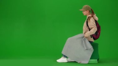 Uçak kreatif havaalanı reklam konseptiyle seyahat etmek. Krom anahtar yeşil ekran arka planında izole edilmiş gezgin portresi. Ekoseyle kaplı oturan, başlık takan, havaalanında şekerleme yapan bir kız..