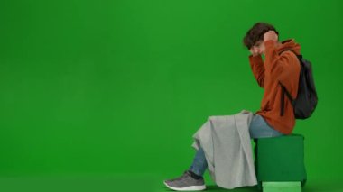 Uçak kreatif havaalanı reklam konseptiyle seyahat etmek. Krom anahtar yeşil ekran arka planında izole edilmiş gezgin portresi. Ekoseyle kaplı oturan, başlık takan, havaalanında şekerleme yapan bir adam..