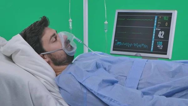 クロマキーグリーンスクリーンの医療区とリハビリテーションクリエイティブコンセプト ドリップ 呼吸マスク モニターでベッドに横たわる大人の患者 目を閉じた 心拍数血圧の兆候が存在しない — ストック写真