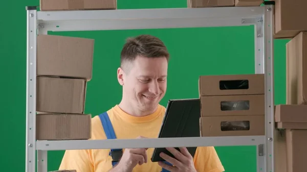 绿色背景相框 铬钥匙 描述是一个穿着工作服的成年男性 演示一个工人 仓库的仓库管理员 他面带微笑地看着一块剪贴板 中型框架 — 图库照片