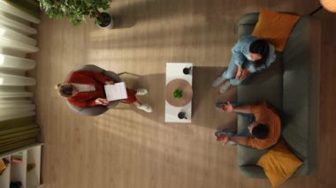 Aile psikoterapisi ve yaratıcı akıl sağlığı konsepti. Terapi seansında evli bir çiftin üst görüntüsü. Bir erkek bir psikologla yapılan konuşmaya olumsuz tepki verir ve bir kadın onu sakinleştirir.