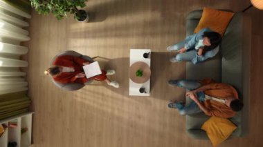 Aile psikoterapisi ve zihinsel sağlık yaratıcı konsepti. Terapi seansındaki evli çiftin en iyi görüntüsü. Kadın ve erkek psikoterapistle konuşuyor ve kavga etmeye başlıyorlar, olumsuz atmosfer..