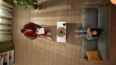 Aile psikoterapisi ve zihinsel sağlık yaratıcı konsepti. Terapi seansındaki en iyi kadın görüntüsü. Kanepede oturmuş psikoterapist dinleyen depresyondaki endişeli bir kadın yastığa sarılıyor..