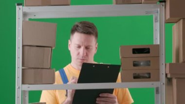 Yeşil arka planda çerçevelenmiş, kromakey. İş üniformalı bir adamı gösteriyor. Depoda bir depocuyu gösteriyor. Depoya kutu saymakla meşgul. Öfkeyle, mutsuz bir şekilde bir şeyler yazıyor..
