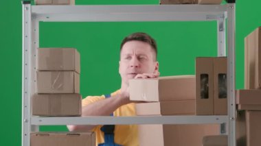 Çerçevede yeşil bir arka plan var. Çalışan üniformalı bir adamı gösteriyor. Depodaki bir depocuyu gösteriyor. Kutuları toplar, sonra düşerler, deliye döner ve diğerlerini dışarı atar..