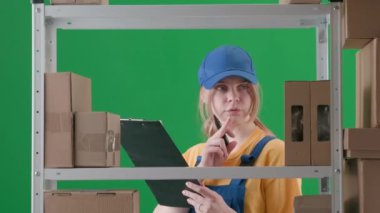 Yeşil arka plan kromatonuna göre çerçevelenmiş. Askeri üniformalı genç bir kadını gösteriyor. Depoda çalışan bir işçiyi, bir depocuyu gösteriyor. Elinde bir dosya tutuyor ve bir rapor tutuyor. Yazıyor.