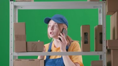 Yeşil arkaplanda, kromakey. Üniformalı genç bir kadın tasvir ediliyor. Depoda bir çalışan tasvir ediliyor. Telefonda biriyle konuşuyor, hareketli hareketler yapıyor, gülümsüyor..