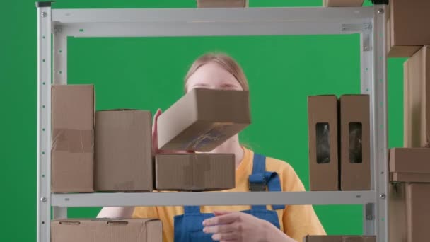 緑色の背景にあるフレームでは 染色体 制服を着た若い女性が描かれている 倉庫に保管庫を置いている労働者です 彼女は箱を集め それらを積み重ね そして葉を残します — ストック動画