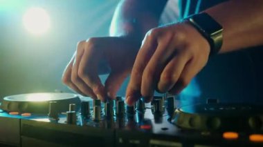 Video, bir DJ 'in becerikli ellerine ses mikserinin düğmelerini ayarlarken, ortam klubünün ışıklandırmasıyla yakınlaşıyor. Kırmızı ellerin canlı kontrastı yeşilin serin tonlarına karşı
