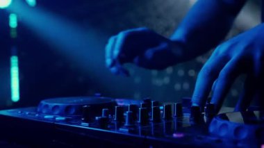 Video, bir DJ 'in becerikli ellerine ses mikserinin düğmelerini ayarlarken, ortam klubünün ışıklandırmasıyla yakınlaşıyor. Kırmızı ellerin canlı kontrastı yeşilin serin tonlarına karşı