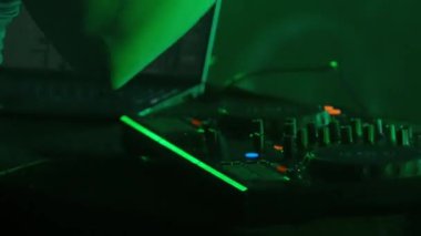 Video, bir DJ 'in becerikli ellerine ses mikserinin düğmelerini ayarlarken, ortam klubünün ışıklandırmasıyla yakınlaşıyor. Kırmızı ellerin canlı kontrastı yeşilin serin tonlarına karşı
