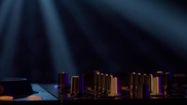 Bu yakın çekim videoda, ses ekipmanlarının karmaşık detaylarını vurgulayan neon lambalarla yıkanmış bir DJ miks tahtası sergileniyor. Pembe ve morlar turntable ve düğmelerde parlıyor