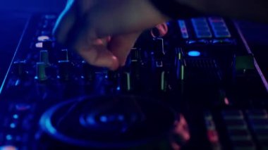 Video, bir DJ 'in becerikli ellerine ses mikserinin düğmelerini ayarlarken, ortam klubünün ışıklandırmasıyla yakınlaşıyor. Kırmızı ellerin canlı kontrastı yeşilin serin tonlarına karşı