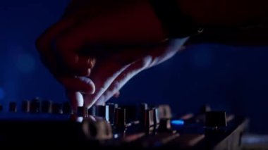 Video, bir DJ 'in becerikli ellerine ses mikserinin düğmelerini ayarlarken, ortam klubünün ışıklandırmasıyla yakınlaşıyor. Kırmızı ellerin canlı kontrastı yeşilin serin tonlarına karşı