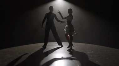 Spotlight 'taki zarif balo dansçısı çift. Bu çarpıcı video, performanslarının ortasında, karanlığa karşı tek bir spot ışığı altında dans eden bir çiftin görüntülerini yakalıyor.
