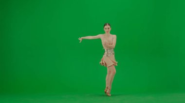 Yeşil Ekran Karşısında Latin Balo Dansçısı. Dengeli bir Latin balo dansçısı yeşil bir perde arkasında duruyor, vücudu zarafet ve kontrol saçıyor. Bej bir dans elbisesi içinde
