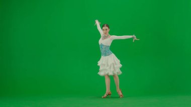 Yeşil Ekran Karşısında Latin Balo Dansçısı. Dengeli bir Latin balo dansçısı yeşil bir perde arkasında duruyor, vücudu zarafet ve kontrol saçıyor. Bej bir dans elbisesi içinde