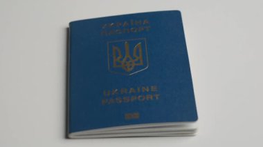 Pasaport ve göç yaratıcı reklam konsepti. Kişinin kimliğini onaylayan bir belgeyi kapat. Beyaz bir masanın üzerinde bir Ukrayna pasaportu var. Bir erkeğin elinden alınan bir pasaport.