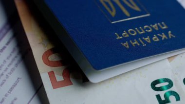 Pasaport ve göç yaratıcı reklam konsepti. Bir kimlik belgesini kapat. Belgeler ve Ukrayna pasaportu. Masada duran kapalı avro banknotları.