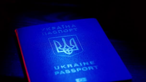 パスポートと移行クリエイティブ広告コンセプト アイデンティティ文書を閉じる ブルーウクライナのパスポート 赤色のライトでテーブルに国家シンボル — ストック動画